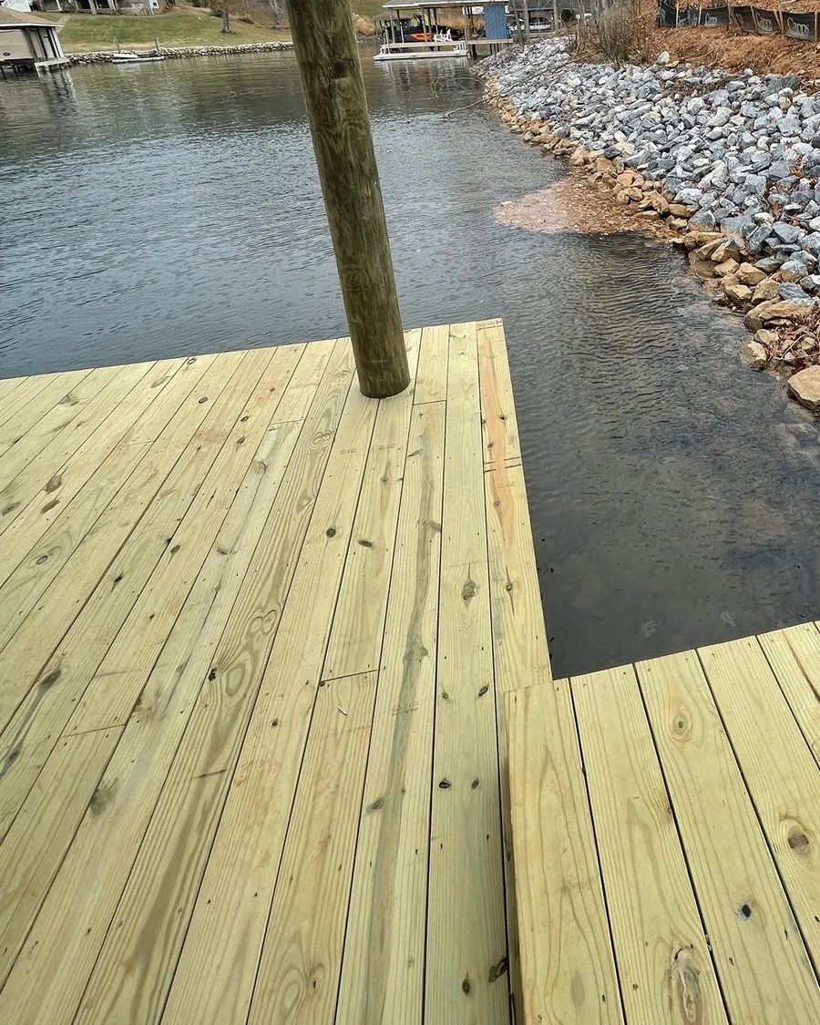 New wood dock decking beside a riprap bank, with a dock post in the foreground